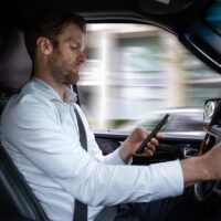 A middle aged caucasian man distracted driving while using a mobile device