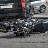 broken motorcycle closeup beside the car. an accident on the road in the city on a sunny day involving a motorcycle and a car.